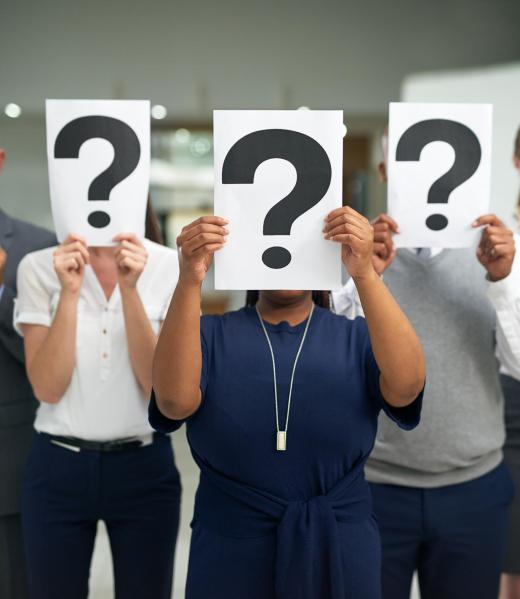 Shot of a group of businesspeople holding questions marks in front of their faces.